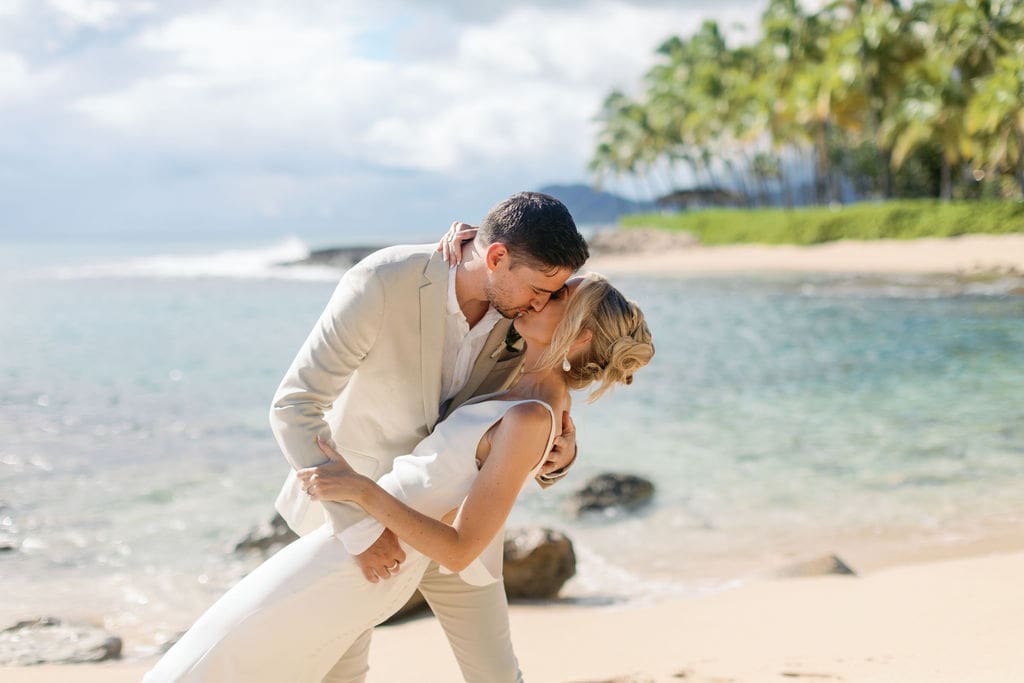 Couple kissing on wedding day at Lanikuhonua beach in Hawaii